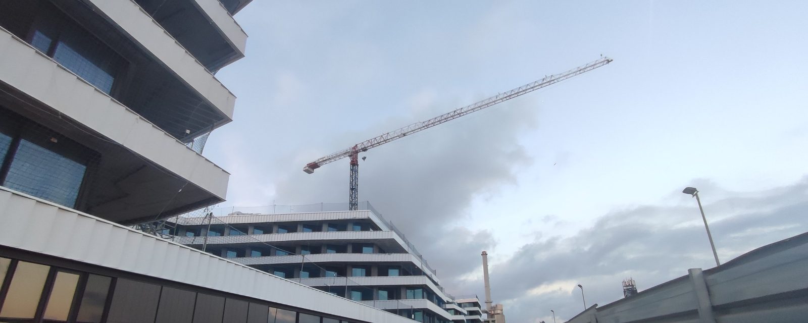 Edifici de l'hotel en obra, amb la grua torre i la xemeneia de la central de climatització